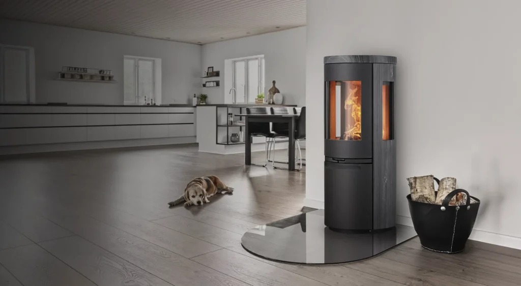 Ett modernt vardagsrum med en vedeldad kamin, synliga lågor, en hund som ligger på trägolvet och en hink med ved i närheten. Rummet har minimalistisk inredning och stora fönster.