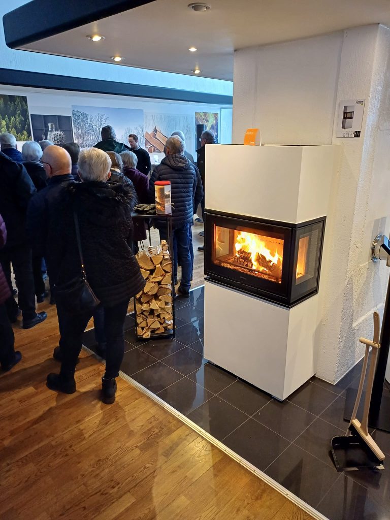 Contura Kaminer: En komplett guide (Modeller, Pris & Test) 2 Personer står samlade runtomkring en braskamin från Contura i deras fabrik i Markaryd