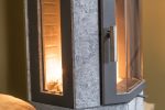 Närbild på Norsk Kleber OCTO+ 110 sidoglas braskamin, med modern design i sten och metall, glasdörr och en varm eld som glöder inuti.