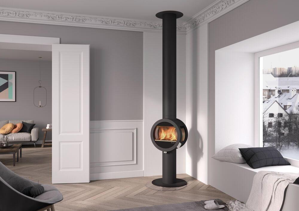 Ett modernt vardagsrum med en elegant, svart vedspis från Nordpeis, ljusgrå väggar, parkettgolv, en mysig fönsterplats med kuddar och ett stort fönster med utsikt över de snöiga hustaken utanför.