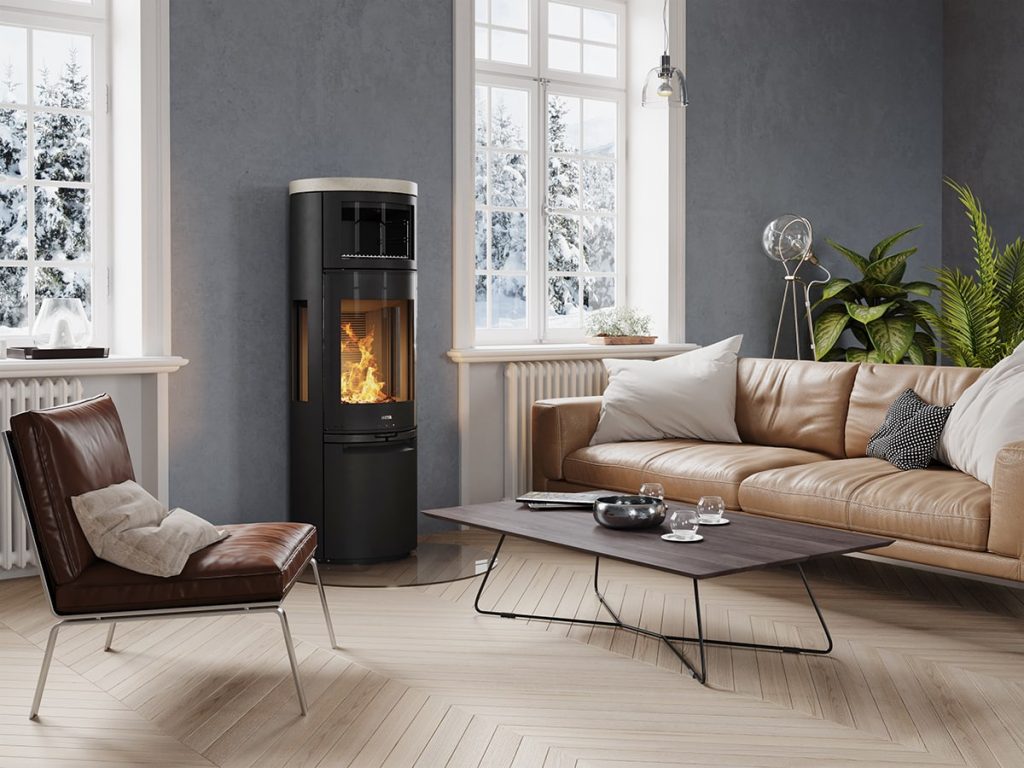 Modernt vardagsrum med en brun skinnsoffa, en brun kuddstol, ett soffbord och en svart kamin med ugn som glöder av eld. Stora fönster avslöjar en snöig utomhusscen, medan gröna växter lyser upp hörnet.