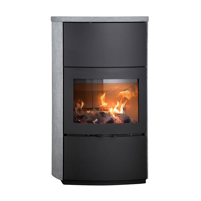 En modern svart värmelagrande kamin med en glasfront som visar en ljus eld inuti, placerad i en rektangulär ram med ljusgrå stensidor och topp.