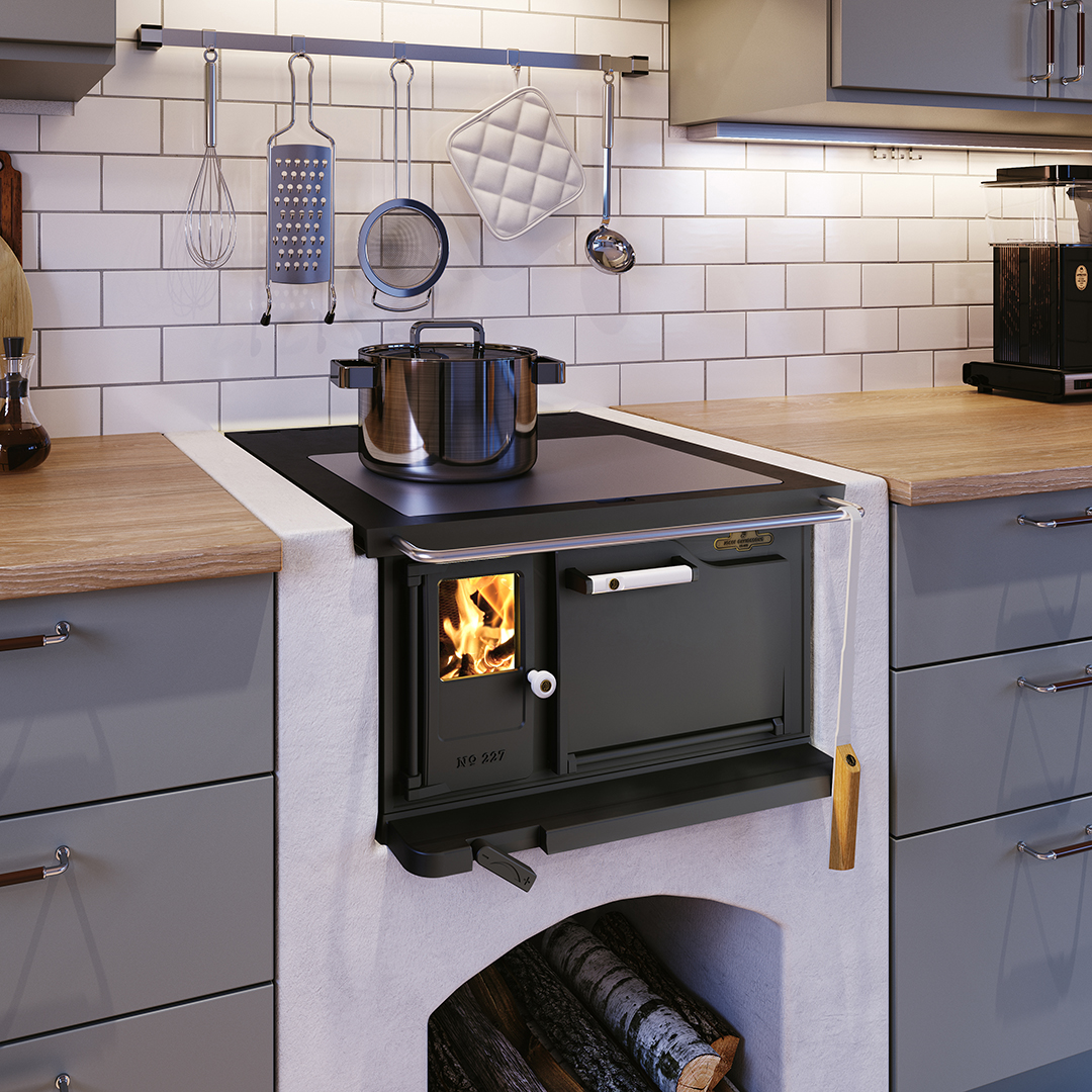 Ett modernt kök med en vedeldad spis inbyggd i en vitkaklad vägg, en kastrull på spisen, köksredskap hängande ovanför och skåp och bänkskivor i trä på båda sidor.