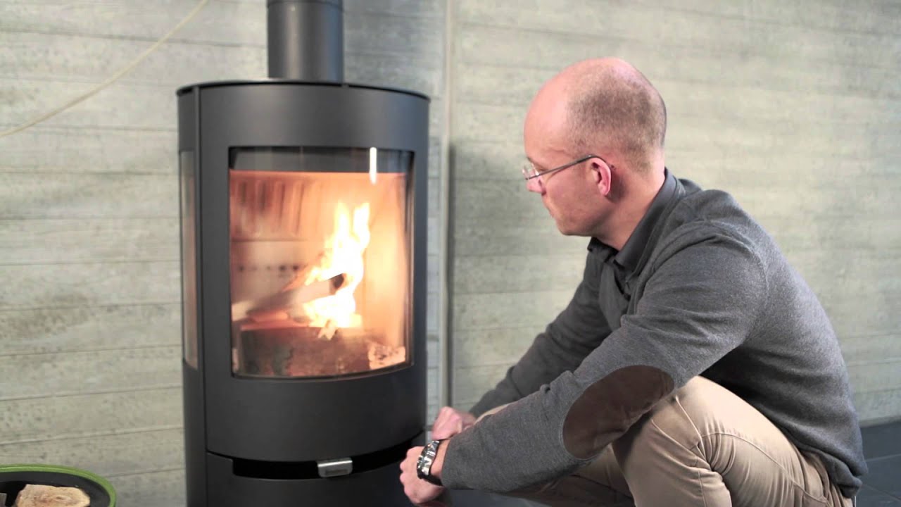 Man sitter framför felaktig braskamin som brinner fint.