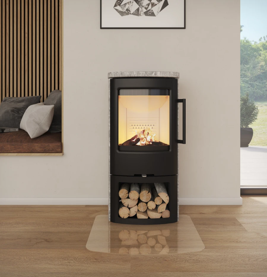 En modern svart braskamin med glasdörr står på en klar eldstadsplatta, med staplad ved nedanför.