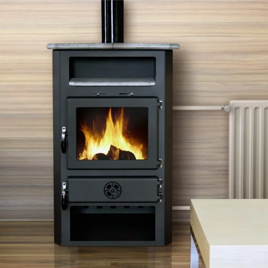 MBS Kaminer & Vedspisar: Den kompletta guiden till ett prisvärt val 2 En modern svart vedspis med synlig eld inuti står mot en träpanelvägg nära ett element och ett ljust soffbord.