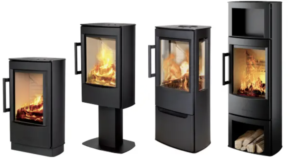 Fyra moderna svarta vedspisar med glasdörrar visas, var och en med en synlig eld som brinner inuti. En av kaminerna står på en piedestal och en annan har ett nedre fack för förvaring av ved.