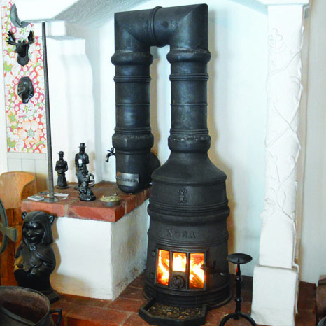 Bergslagskamin: En guide till den klassiska kaminen 4 En bergslagskamin i en källare med brinnande låga.